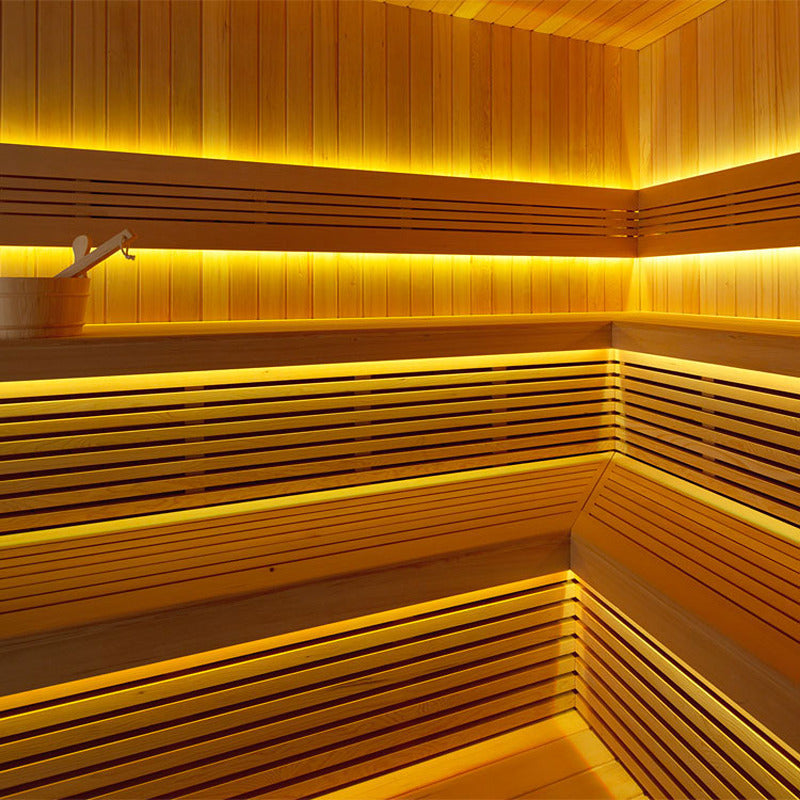 Modernes Sauna-Innenleben aus Hemlockholz mit gelber LED-Ambientebeleuchtung auf mehreren Ebenen
