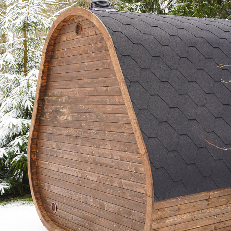 Celsium Herkus Small Gartensauna im Winter, Rückansicht mit schwarzem Bitumendach und verschneiter Umgebung.
