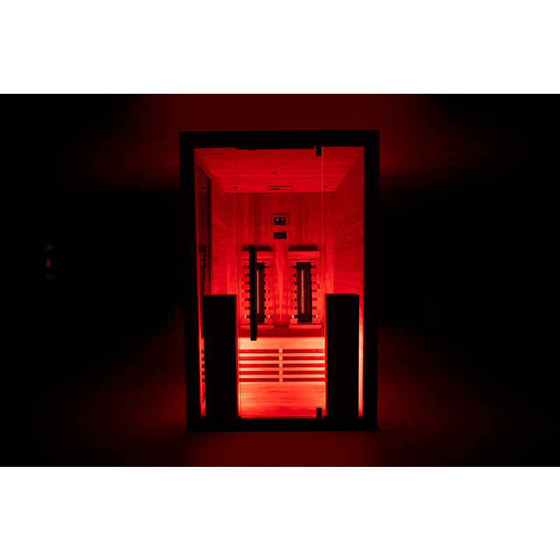 Frontalansicht der beleuchteten Infrarotkabine mit intensiver roter Lichtstimmung bei Dunkelheit