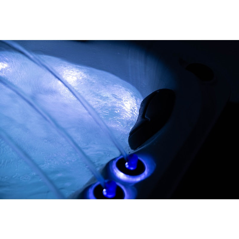 Platinum Spas Tahiti Hot Tub – Nahaufnahme bei Nacht mit blauen LED-beleuchteten Fontänen und ergonomischer Kopfstütze für ein luxuriöses Entspannungserlebnis