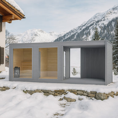 Moderne Gartensauna Tauras Balance in grauem Holzdesign neben einer Chalet-Villa im verschneiten Skigebiet, umgeben von Alpenpanorama und winterlicher Naturkulisse – stilvolle Outdoor-Wellness im Schnee.
