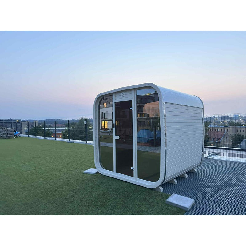 Celsium Ula Small Outdoor Sauna in Weiß mit Glasfront auf Dachterrasse bei Abenddämmerung – stilvolle Wellness-Oase mit urbanem Panorama
