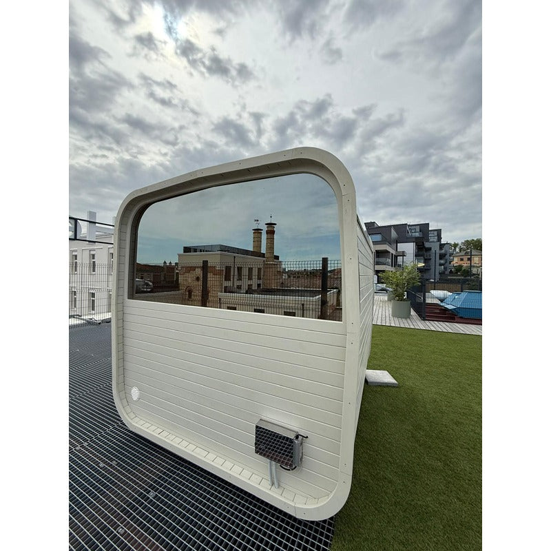 Rückansicht der Celsium Ula Small Outdoor Sauna in Weiß mit großem getöntem Panoramafenster – stilvolle Außensauna mit urbanem Ausblick