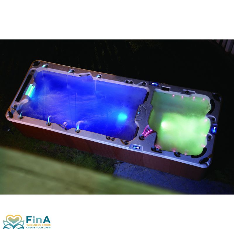 Nachtaufnahme des FinA Hydronyx Whirlpools – eindrucksvolle LED-Beleuchtung in Blau und Grün, die Wasser und Umgebung stimmungsvoll in Szene setzt.