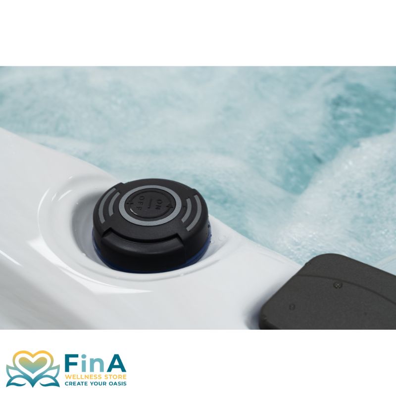 Detailaufnahme eines Bedienknopfes am FinA Xaluna Outdoor Whirlpool, eingelassen in die Acrylwanne mit Wasser im Hintergrund