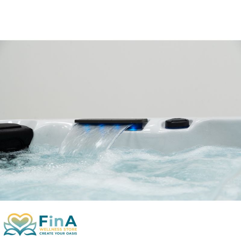 Seitliche Detailansicht des FinA Xaluna Outdoor Whirlpools mit beleuchtetem Wasserfall-Auslass, sprudelndem Wasser und integrierter Steuerung.