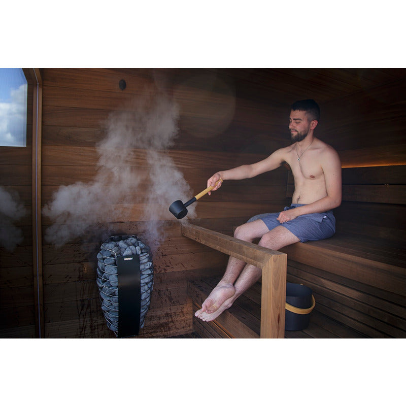 Mann genießt Saunaaufguss mit Harvia Spirit Elektro-Saunaofen, stilvoll eingebaut in moderner Holzsauna