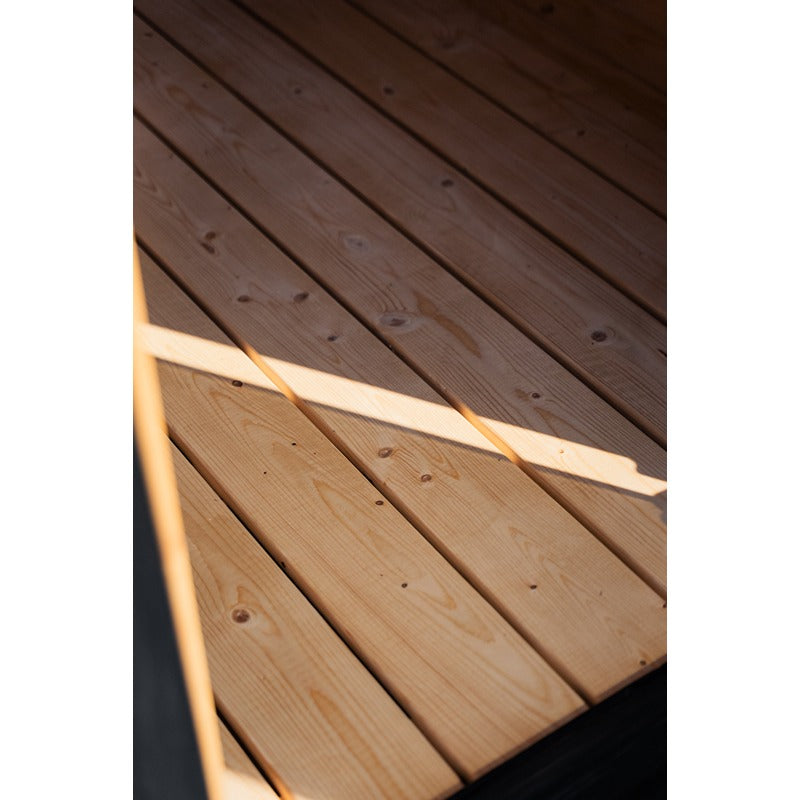 Detailaufnahme des naturbelassenen Holzbodens der Ula Large Sauna mit Licht- und Schattenspiel