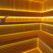 Modernes Sauna-Innenleben aus Hemlockholz mit gelber LED-Ambientebeleuchtung auf mehreren Ebenen