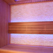 Infrarotkabine mit roten Zedernholzbänken, rosa beleuchtete Rückwand und seitlichen Wandpaneelen, modernes Design mit horizontaler Holzstruktur