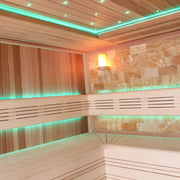 Moderne Sauna aus roter Zeder mit grüner LED-Beleuchtung an Decke und Wand, Salzstein-Panel und hölzernen Sitzbänken im Inneren
