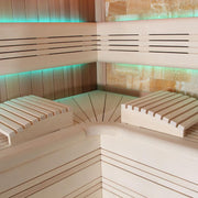 Innenansicht einer modernen Sauna mit Holzbänken aus roter Zeder, türkisem LED-Licht und ergonomischem Design für mehrere Personen.