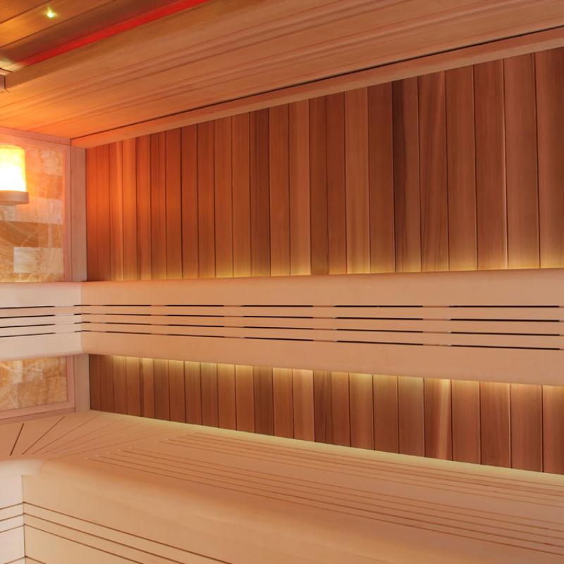 Innenansicht der EAGO AWT E1400B Sauna aus roter Zeder mit breiten Holzbänken, vertikal lamellierter Wandverkleidung und warmweißer Beleuchtung
