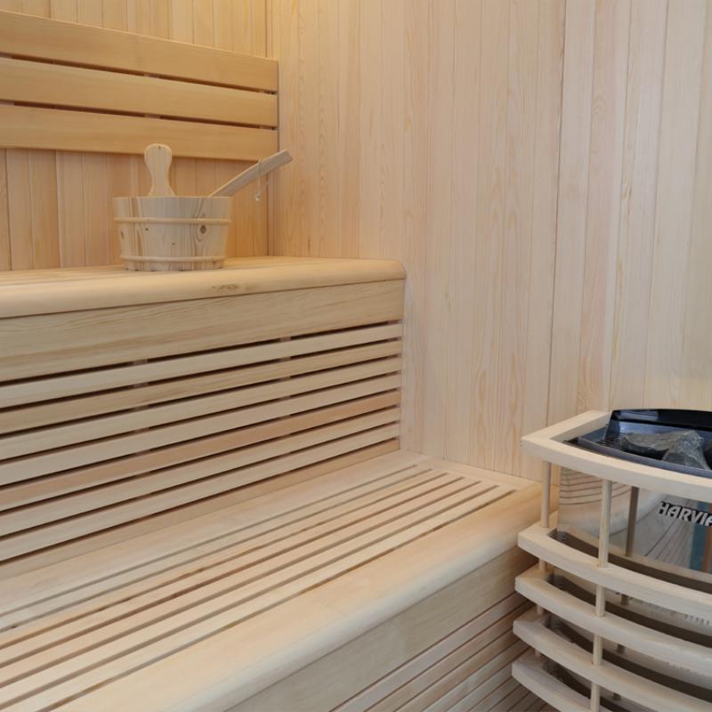Innenansicht der EAGO AWT E1801A Sauna aus Pinienholz mit Bänken, Kübel und Kelle, moderner Saunaofen sichtbar