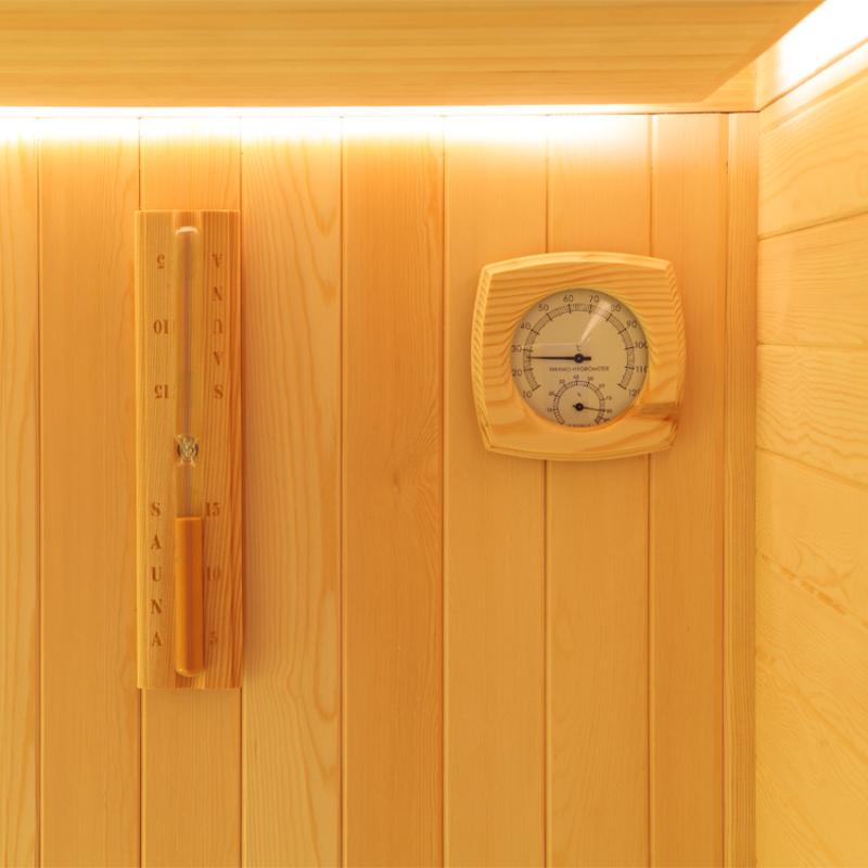 Saunainnenraum mit Holzverkleidung, Saunaofen und Holzthermometer an der Wand