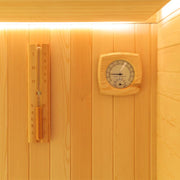 Saunainneres aus hellem Fichtenholz mit Holzthermometer und Hygrometer an der Wand sowie Aufgusslöffel und Holzeimer links