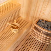 Innenansicht der EAGO AWT E1811B Sauna aus Pinienholz mit Saunabänken, Holzkelle und Saunasteine in der Ecke