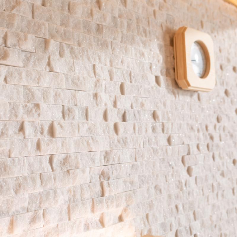 Digitales Thermometer mit Holzrahmen an einer hellen Backstein-Wandverkleidung montiert