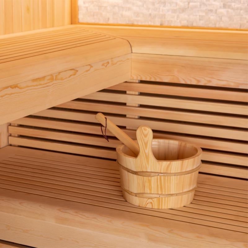 Detailaufnahme einer Saunaliege mit Holzeimer und Kelle in einer geräumigen Pinienholz-Sauna