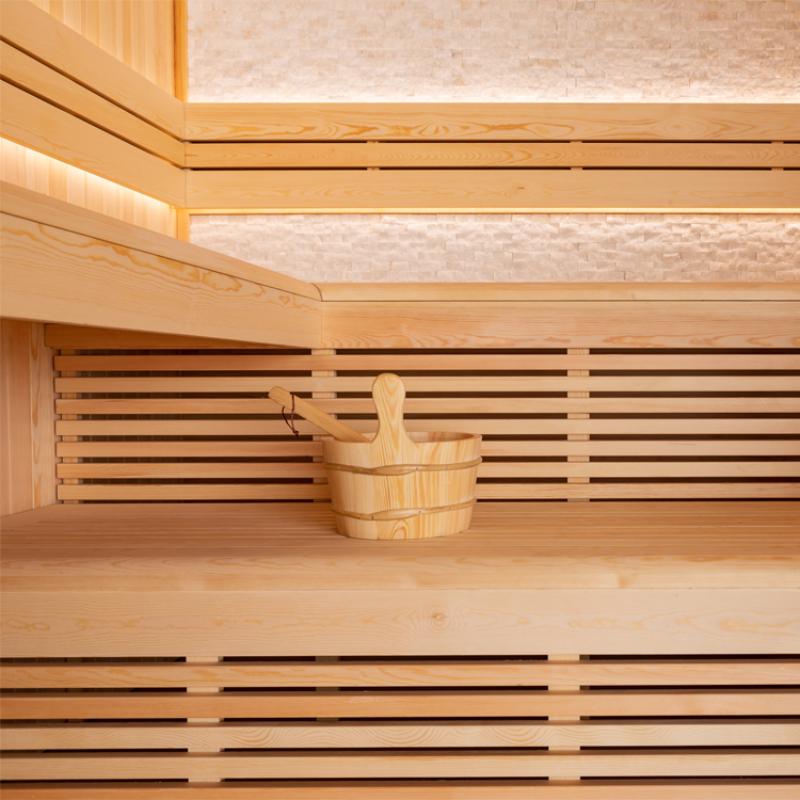 Holzsauna aus Pinienholz mit Saunakübel und Kelle auf der Sitzbank, modernes minimalistisches Design mit horizontalen Holzlatten und Oberlicht