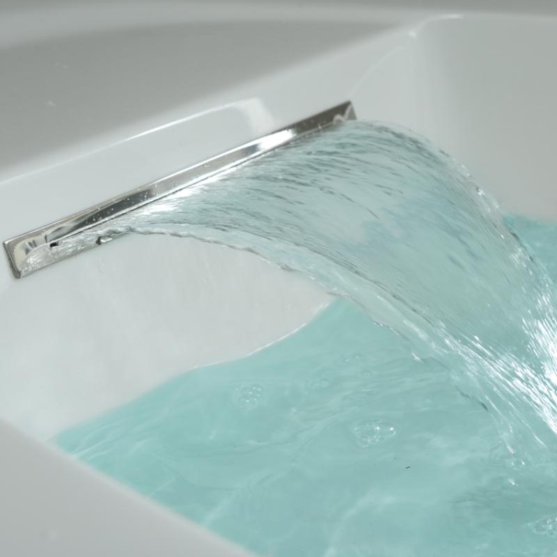 Wasserstrahl aus verchromtem Auslauf in weiße Whirlpool-Wanne mit türkisblauem Wasser