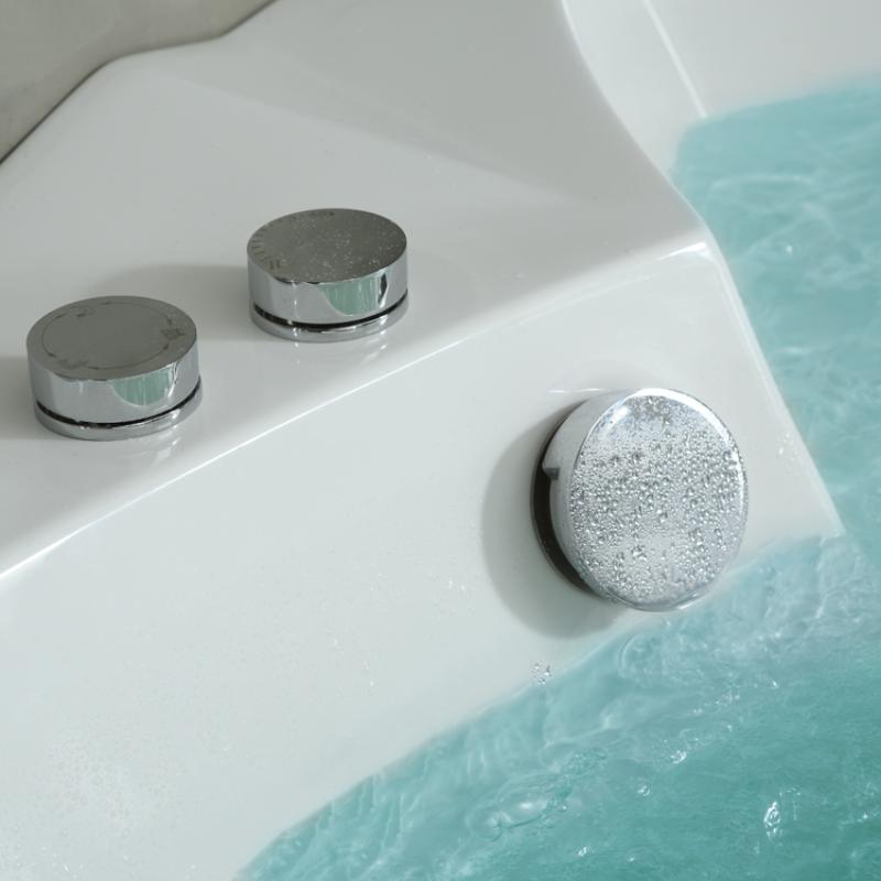 Whirlpool-Armaturenset mit zwei verchromten Drehreglern und rundem Luftventil auf weißem Badewannenrand über türkisblauem Wasser