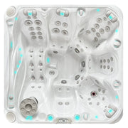 Draufsicht auf den Passion Spas Admire Whirlpool mit weißem Kunststoffgehäuse, zahlreichen Massagedüsen, türkisen LED-Leuchten und Bedienfeldern für 6 Personen
