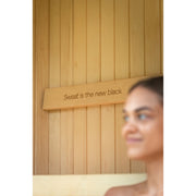 Detail der Innenwand mit Schriftzug „Sweat is the new black“ – stilvolles Design-Element in der Celsium Jonas Small Sauna aus Naturholz.