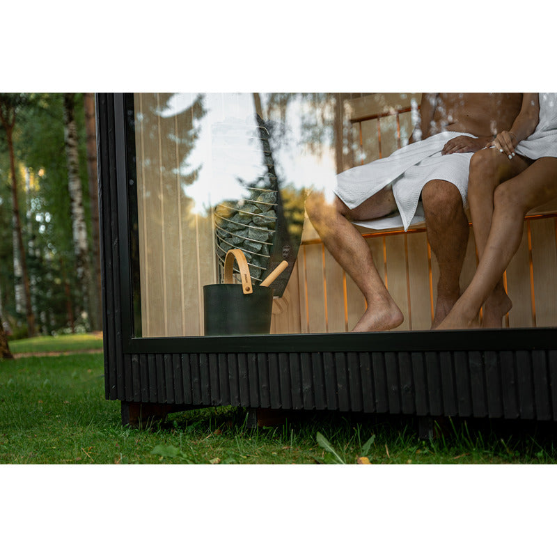 Nahaufnahme Saunaeimer und Ofen in der Celsium Jonas Small Glassauna – moderne Outdoor Sauna mit klarer Glasfront und dunkler Holzverkleidung.
