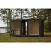 Moderne Gartensauna Tauras View mit dunkler Holzverkleidung und Glasfront, freistehend inmitten eines Waldes am Seeufer – harmonische Verbindung von Design und Natur.
