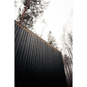 Schwarze Holzfassade der Celsium Jonas Grand Gartensauna mit umlaufender LED-Lichtlinie.
