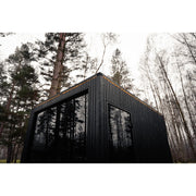 Celsium Jonas Grand Gartensauna in schwarzer Holzoptik mit Glasfront im Wald.
