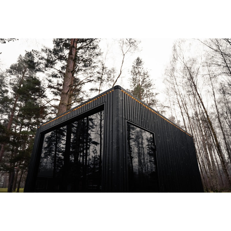 Celsium Jonas Grand Gartensauna in schwarzer Holzoptik mit Glasfront im Wald.
