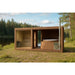 Moderne Gartensauna mit integriertem Whirlpool aus Holz, aufgestellt in einer natürlichen Umgebung am Seeufer, umgeben von grünen Bäumen und blauem Himmel.