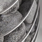  Detailansicht: HUUM Saunaofen mit dicht geschichteten, runden Saunasteinen aus Olivin-Diabas