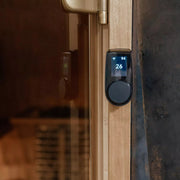 Digitale Saunasteuerung HUUM UKU in Schwarz an Holztür montiert, Display zeigt Temperatur 94°C und Zeit 26 Minuten