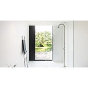Moderne JEE-O Original Dusche 01 mit silberner Steigrohrarmatur in minimalistischem Badezimmer mit großem Fenster und Garderobenstab, Blick ins Grüne