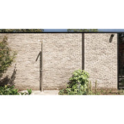 JEE-O Pure Dusche 01 in minimalistischem Design an Backsteinmauer eines modernen Hauses mit Gartenpflanzen