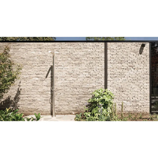 JEE-O Pure Dusche 01 in minimalistischem Design an Backsteinmauer eines modernen Hauses mit Gartenpflanzen