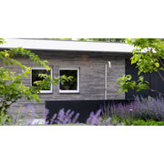 Moderne Gartendusche JEE-O Soho 01 mit Edelstahlkopf an zeitgenössischem Holzhaus, umgeben von blühenden Lavendelbeeten und grünen Pflanzen