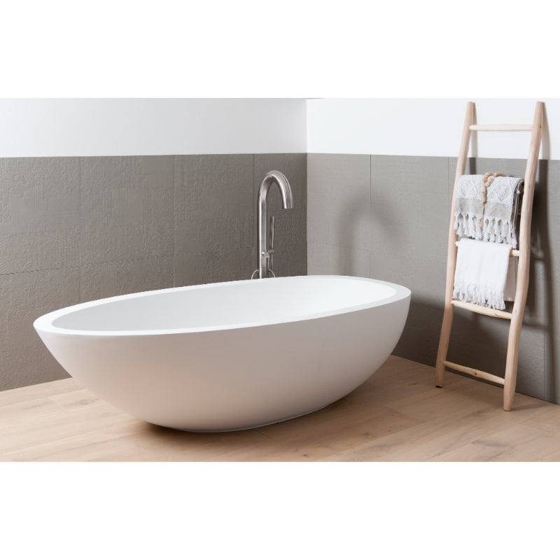 Freistehende weiße Badewanne mit eleganter Kurvenform und chromfarbener JEE-O Standarmatur in modernem Badezimmer mit Holzleiter und weißen Handtüchern