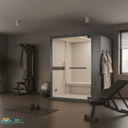 Novellini Celsius Hammam Dampfbadkabine in einem modernen Home-Gym mit Fitnessbank, Kraftstation und Hanteln – stilvolle Integration von Wellness und Training.