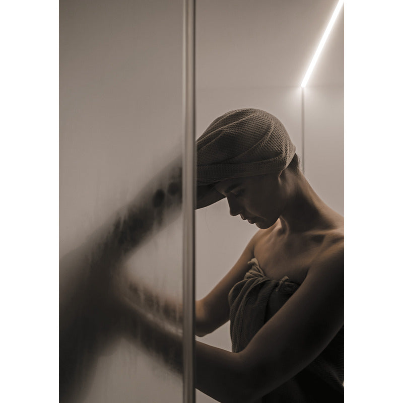 Frau in entspannter Haltung im Inneren der Celsius Hammam Dampfbadkabine – feuchter Dampf auf Glas, stimmungsvolle Lichtinszenierung.