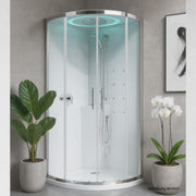 Moderne Runddusche Novellini EON R mit Glaswänden und LED-Beleuchtung, stilvoll integriert in einen hellen Raum mit Ziegelwand, Zimmerpflanzen und abstrakter Wandkunst.