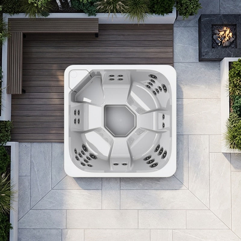 Draufsicht auf weißen Novitek S-0 Outdoor Whirlpool mit achteckiger Form, Massagedüsen und zentralem Becken auf Terrassenplatz mit Holzdeck und Natursteinbelag