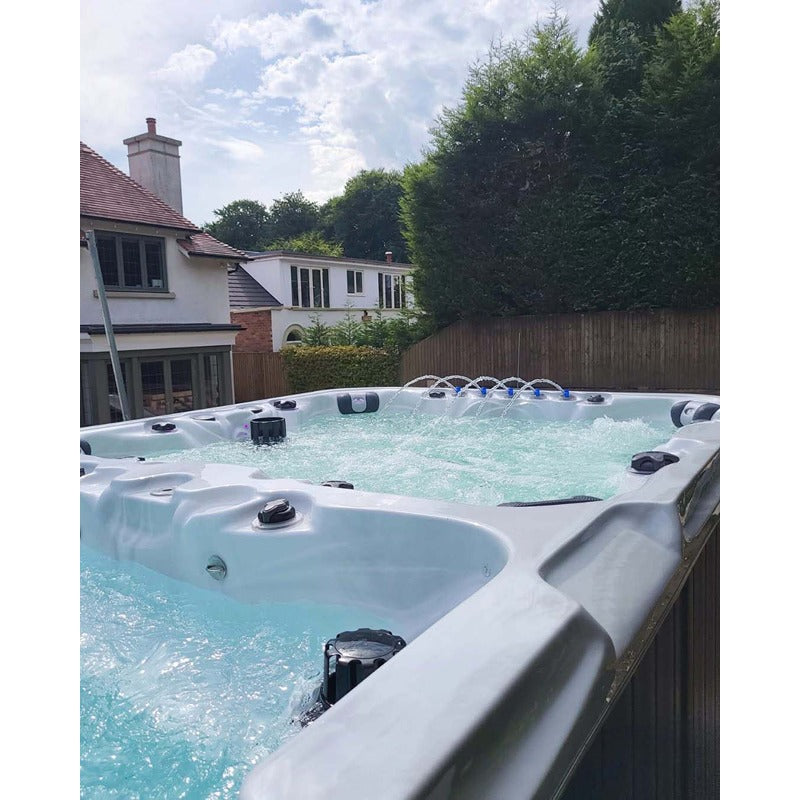 Passion Spas Vitality Swim Spa mit Wasserfontänen im Garten bei Tageslicht