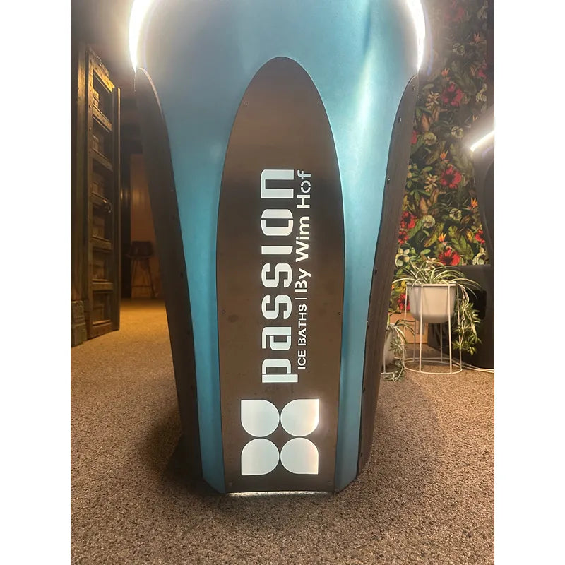 Passion Revive Pro Eisbad mit ovalem Design, türkis-blauer Außenseite und schwarzem Branding, ausgestellt in einem modernen Showroom mit LED-Beleuchtung