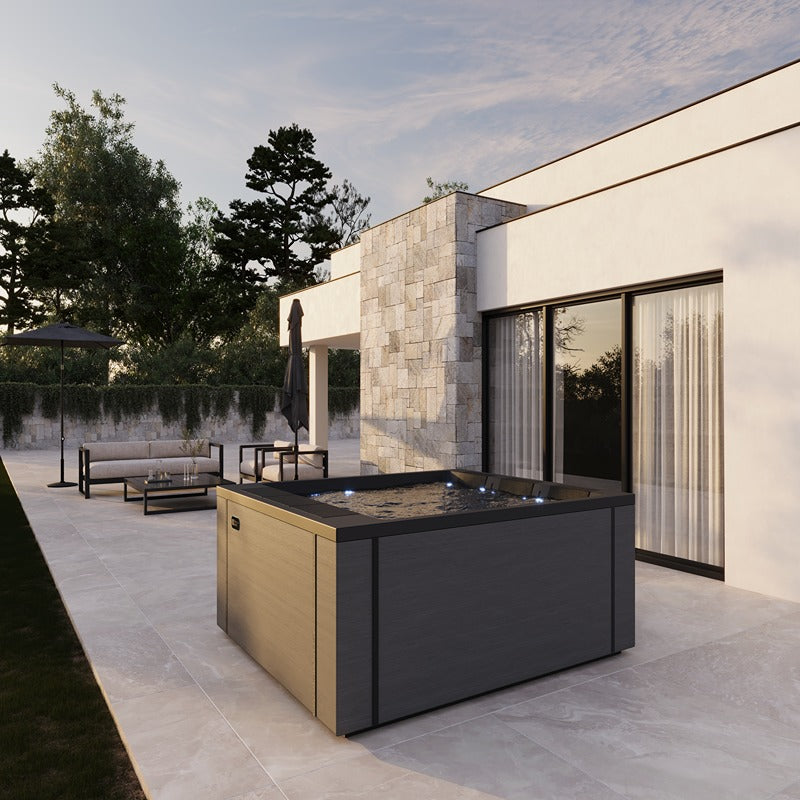 Outdoor-Installation des Lounge Divine Plus Whirlpools auf einer stilvollen Terrasse – luxuriöses Spa-Erlebnis im eigenen Garten bei Sonnenuntergang.