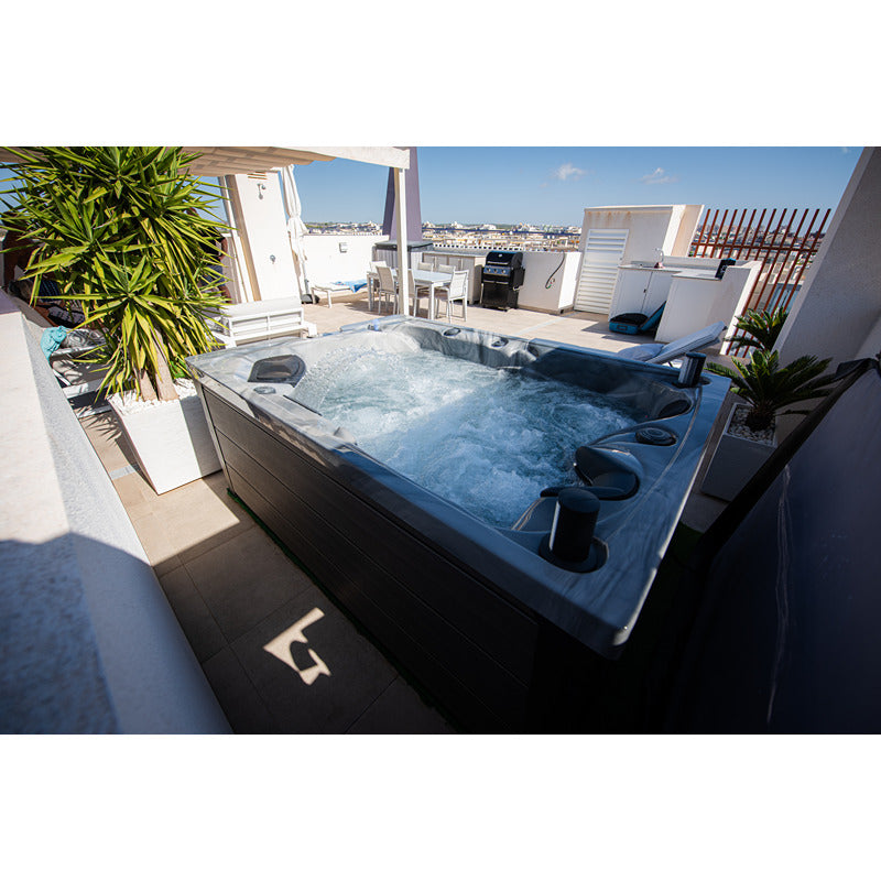Stilvoller Whirlpool Platinum Spas Topaz – Premium auf Dachterrasse mit Ausblick über die Stadt. Wasser sprudelt bei eingeschaltetem Betrieb