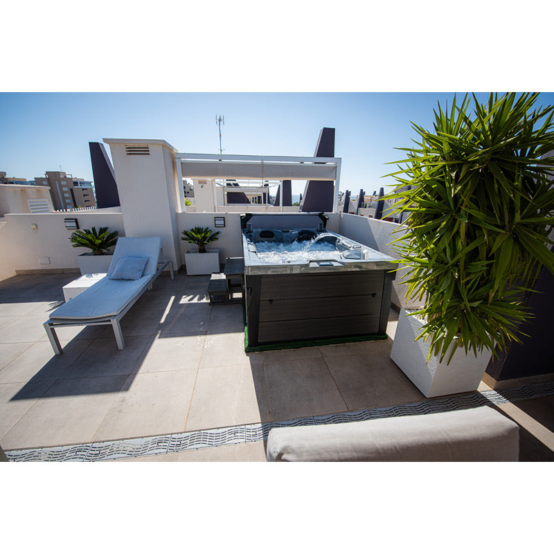 Platinum Spas Topaz Outdoor Whirlpool mit sprudelndem Wasser auf einer sonnigen Dachterrasse, umgeben von Pflanzen und Liegestuhl